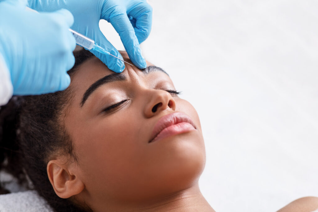 Patient receiving Botox injection in the frown lines area at a plastic surgery clinic