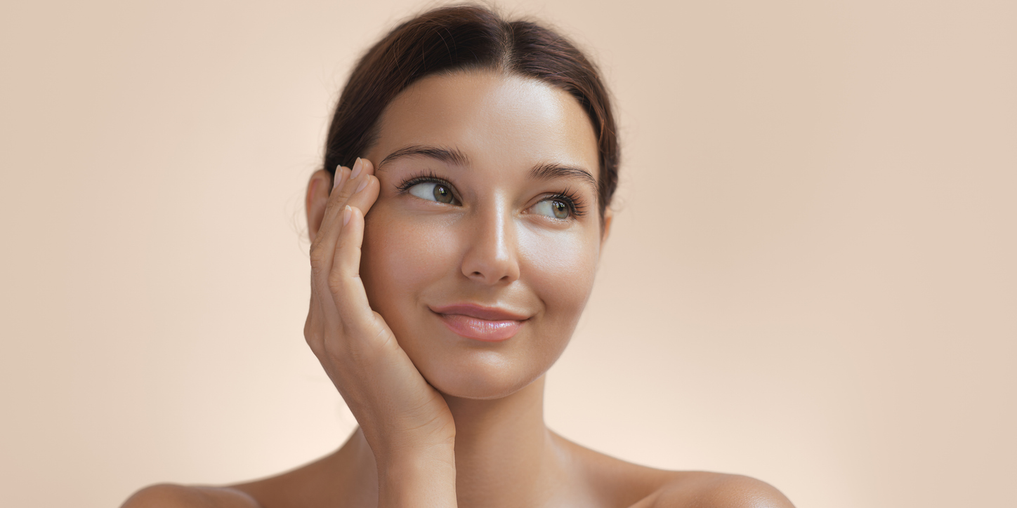 Woman with eyes closed touching her face with glow from a facial in Sugar Land, TX